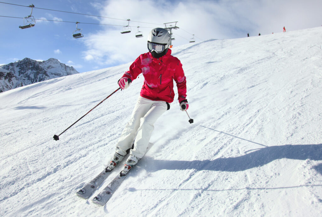 Best women's ski jackets: woman skiing in red jacket with chairlift in the background